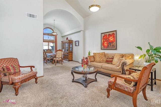 carpeted living area with visible vents, high vaulted ceiling, and baseboards