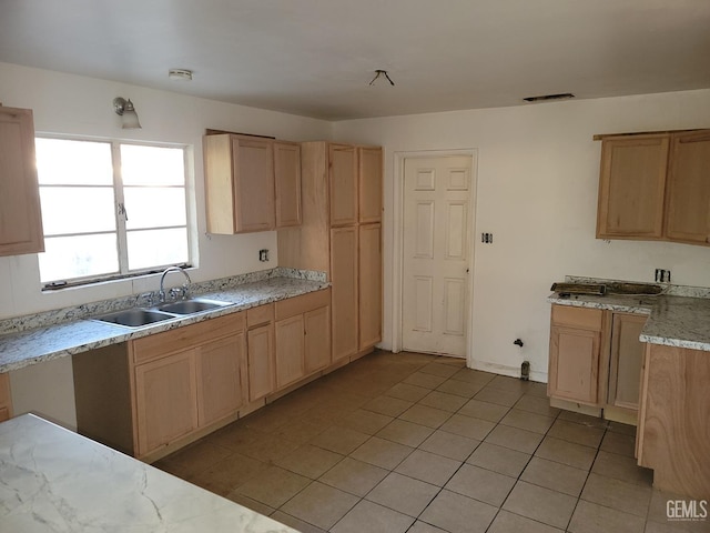 kitchen with light tile patterned floors, visible vents, light brown cabinets, and a sink