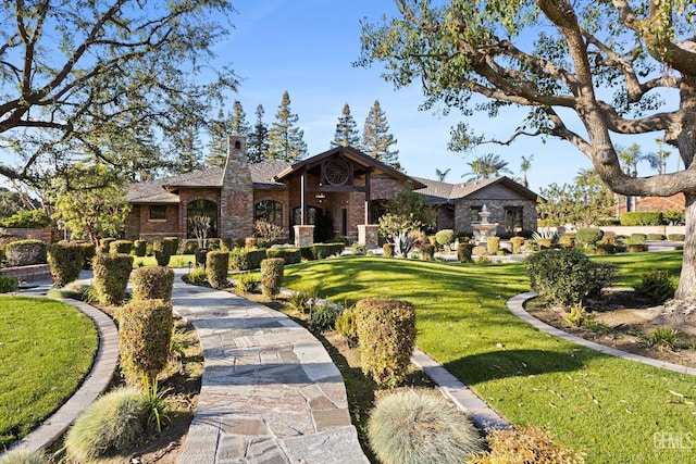 view of front facade featuring a front lawn, a chimney, and brick siding