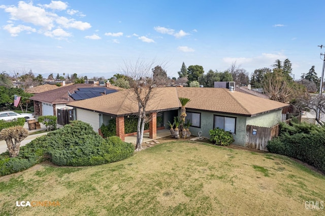 ranch-style house with a garage, a front lawn, and solar panels