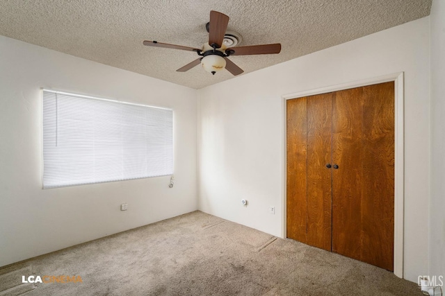 unfurnished bedroom with ceiling fan, carpet, a textured ceiling, and a closet