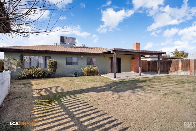 rear view of house featuring a yard, central AC, and a patio area