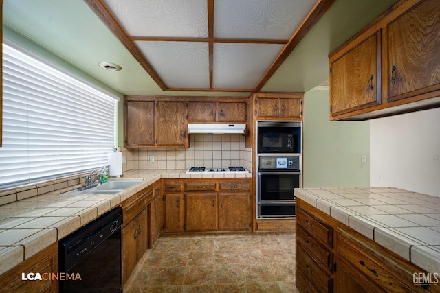 kitchen with backsplash, tile counters, sink, and black appliances