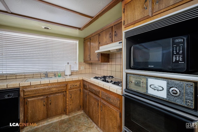 kitchen featuring backsplash, tile counters, black appliances, and sink