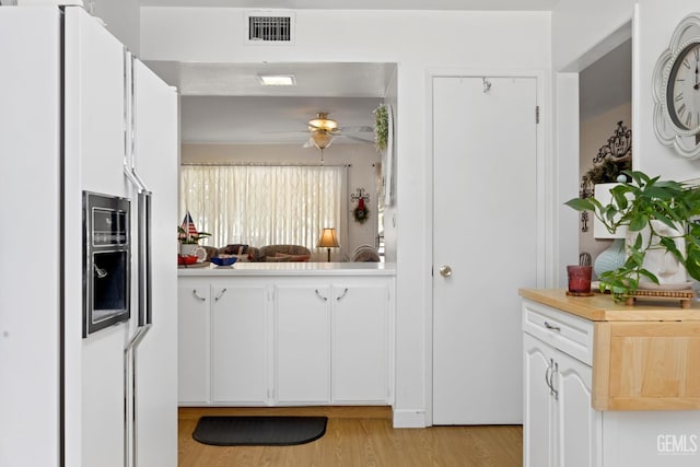 1112 Pebble Beach Dr, Bakersfield, CA 93309 - kitchen featuring white fridge with ice dispenser, light countertops, ceiling fan, white cabinets, and light wood-style floors