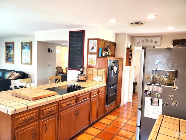 6333 Crestmore St, Bakersfield, CA 93308 - kitchen with black appliances, a peninsula, tile counters, open floor plan, and recessed lighting