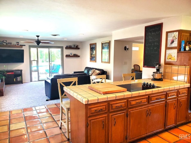 6333 Crestmore St, Bakersfield, CA 93308 - kitchen with open floor plan, tile counters, black electric stovetop, ceiling fan, and light colored carpet