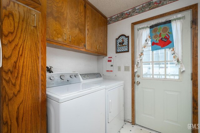 laundry area with washing machine and clothes dryer, cabinets, and a textured ceiling