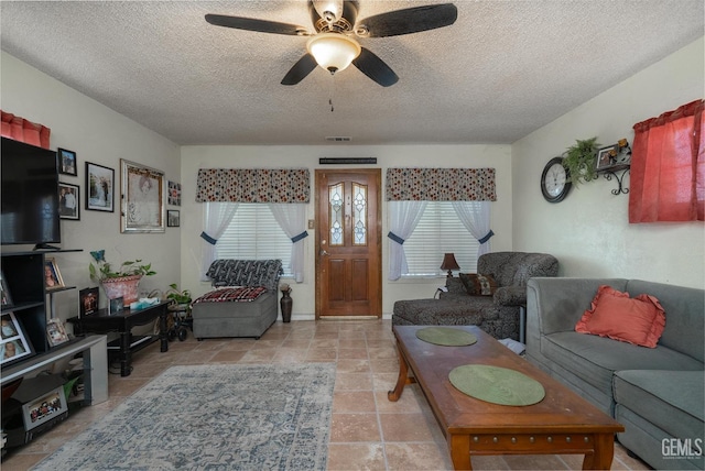 living room featuring ceiling fan and a textured ceiling