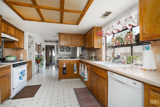 kitchen with decorative backsplash, white appliances, sink, and kitchen peninsula