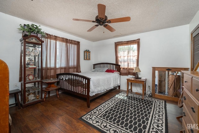 bedroom featuring multiple windows, ceiling fan, dark wood-type flooring, and a textured ceiling