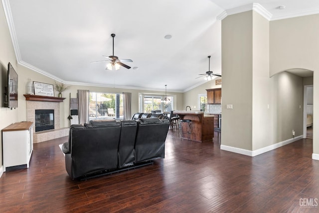 living room featuring dark hardwood / wood-style flooring, crown molding, a fireplace, and ceiling fan