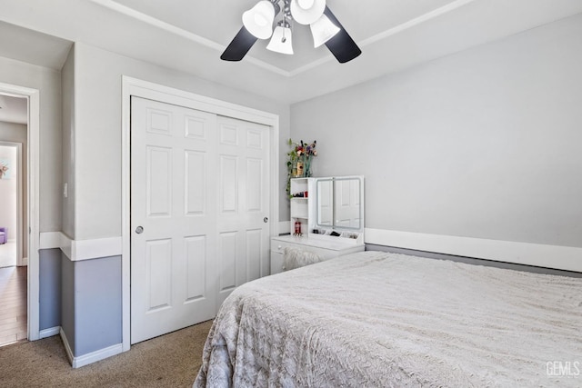 carpeted bedroom featuring ceiling fan and a closet