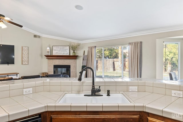 kitchen featuring plenty of natural light, tile countertops, dishwashing machine, and sink