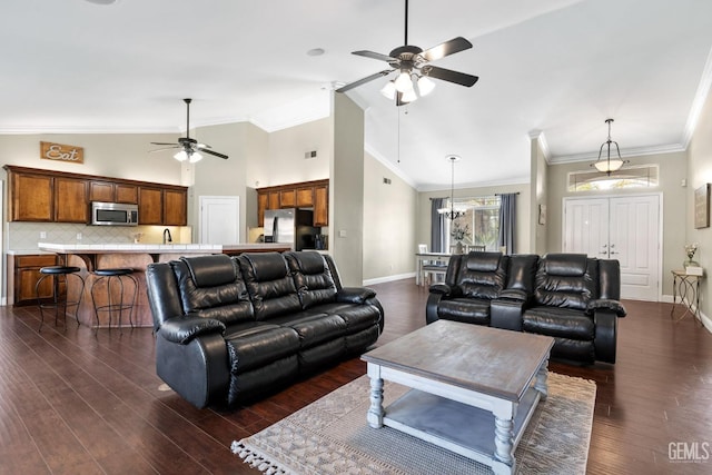 living room with crown molding, dark hardwood / wood-style floors, ceiling fan with notable chandelier, and high vaulted ceiling