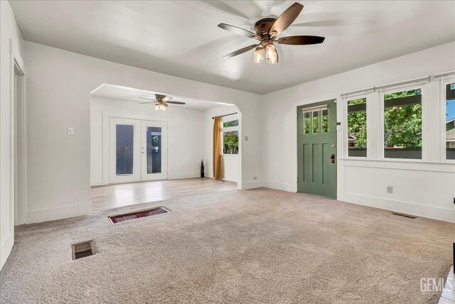 930 S Roosevelt Ave, Fresno, CA 93728 - unfurnished living room featuring light carpet, a ceiling fan, baseboards, and arched walkways