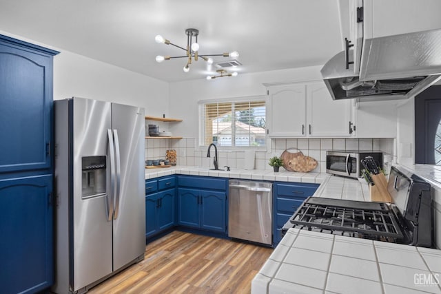 6418 Abby Rose Ave, Bakersfield, CA 93308 - kitchen featuring stainless steel appliances, blue cabinets, tile countertops, tasteful backsplash, and a chandelier