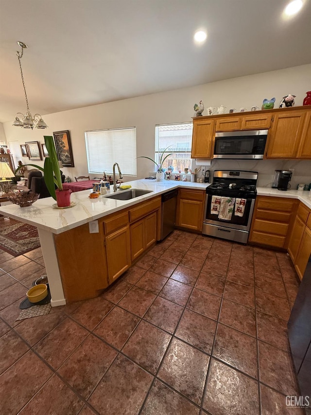 3910 Mariana Way, Bakersfield, CA 93311 - kitchen featuring appliances with stainless steel finishes, hanging light fixtures, brown cabinets, recessed lighting, and light stone countertops