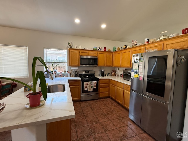3910 Mariana Way, Bakersfield, CA 93311 - kitchen with appliances with stainless steel finishes, brown cabinets, a peninsula, light stone countertops, and dark tile patterned floors