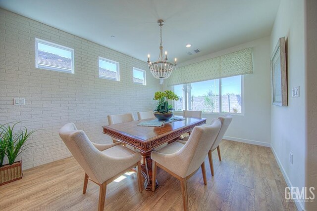 11022 Irontooth Ave, Bakersfield, CA 93311 - dining area featuring a chandelier, light wood-style flooring, brick wall, and baseboards