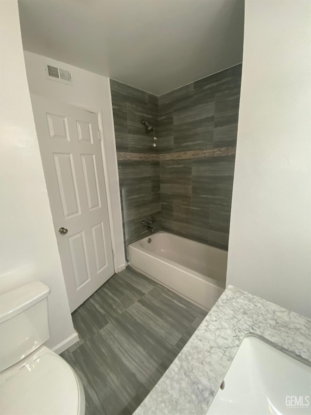 bathroom featuring toilet and tiled shower / bath