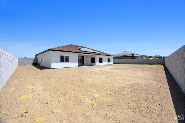 205 Goertzen Ave, Shafter, CA 93263 - back of property featuring roof mounted solar panels, a fenced backyard, and stucco siding