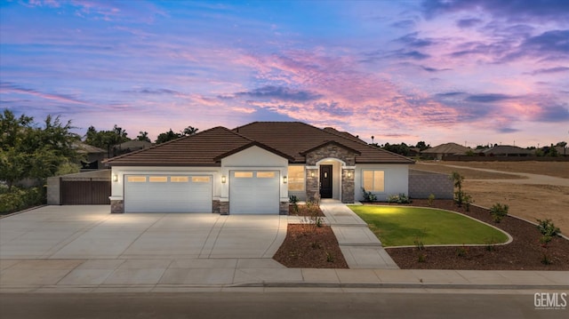 205 Goertzen Ave, Shafter, CA 93263 - view of front of property featuring driveway, stone siding, an attached garage, a front yard, and stucco siding