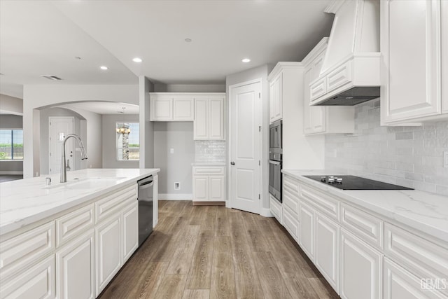 205 Goertzen Ave, Shafter, CA 93263 - kitchen with custom range hood, stainless steel appliances, arched walkways, white cabinets, and a chandelier