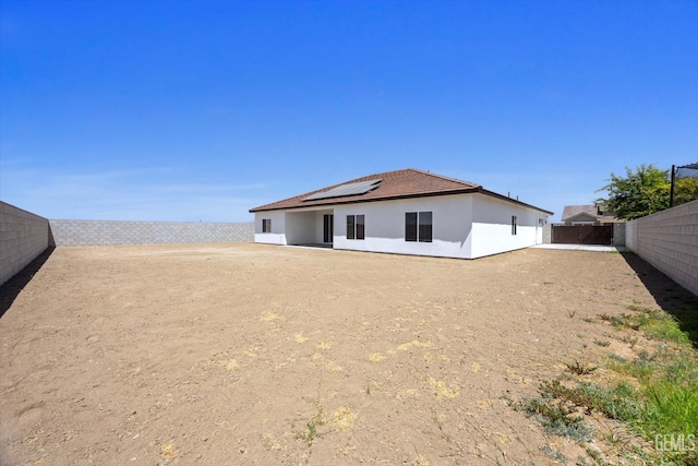 205 Goertzen Ave, Shafter, CA 93263 - back of property featuring roof mounted solar panels, a fenced backyard, and stucco siding