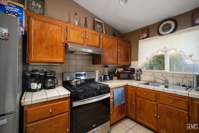 1701 San Jose Ave, Wasco, CA 93280 - kitchen with stainless steel appliances, under cabinet range hood, a sink, backsplash, and brown cabinets