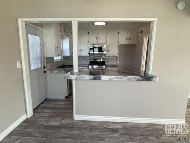 132 Franklin Ave, Taft, CA 93268 - kitchen featuring dark wood finished floors, a peninsula, appliances with stainless steel finishes, a sink, and baseboards