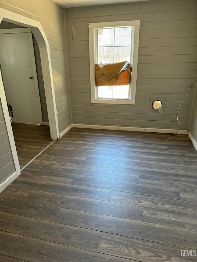 interior space with dark hardwood / wood-style floors and wooden walls