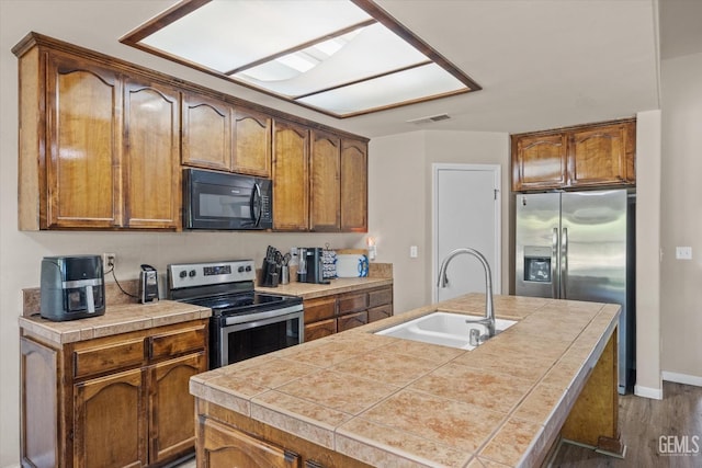 5502 Veneto St, Bakersfield, CA 93308 - kitchen featuring appliances with stainless steel finishes, a sink, dark wood-style flooring, and brown cabinets