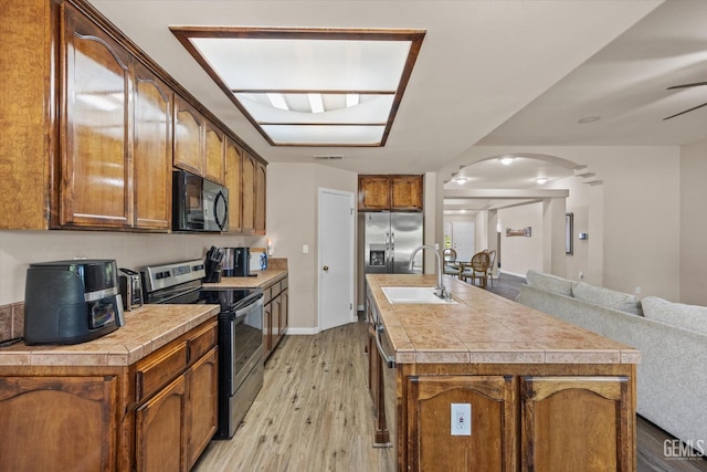 5502 Veneto St, Bakersfield, CA 93308 - kitchen featuring appliances with stainless steel finishes, arched walkways, a sink, light wood finished floors, and light countertops
