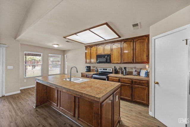 5502 Veneto St, Bakersfield, CA 93308 - kitchen with black microwave, electric stove, a sink, dark wood-type flooring, and a center island with sink