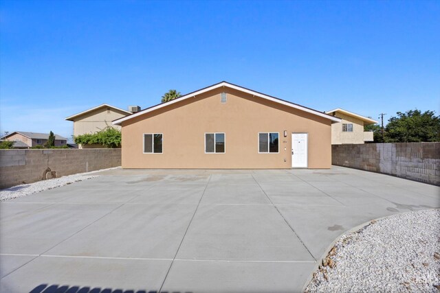 135 L St, Bakersfield, CA 93304 - back of property featuring a fenced backyard, stucco siding, and a patio area
