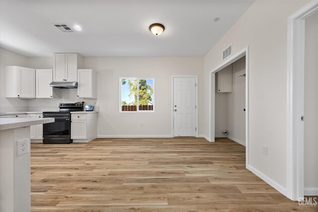 135 L St, Bakersfield, CA 93304 - kitchen with black electric range, under cabinet range hood, light countertops, light wood finished floors, and recessed lighting