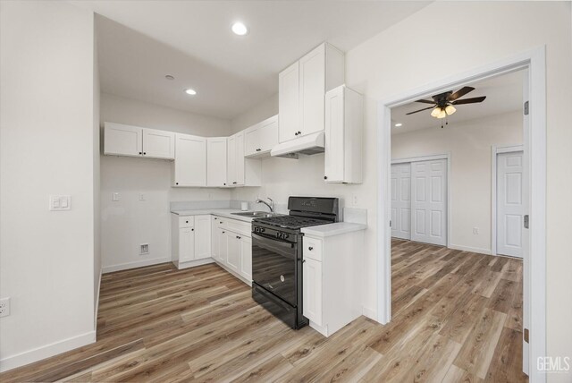 135 L St, Bakersfield, CA 93304 - kitchen featuring black gas range, under cabinet range hood, light wood finished floors, light countertops, and recessed lighting