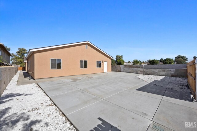 135 L St, Bakersfield, CA 93304 - rear view of property featuring a fenced backyard, stucco siding, and a patio area