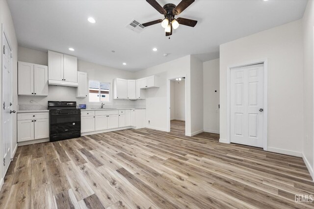 135 L St, Bakersfield, CA 93304 - kitchen with black range, ceiling fan, light wood-type flooring, white cabinetry, and light countertops