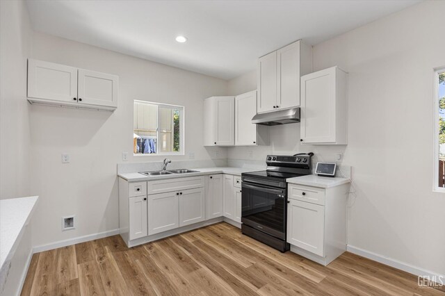 135 L St, Bakersfield, CA 93304 - kitchen with electric range, under cabinet range hood, light wood-type flooring, white cabinetry, and light countertops