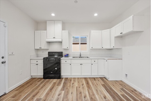 135 L St, Bakersfield, CA 93304 - kitchen with black gas stove, light wood-type flooring, white cabinets, light countertops, and recessed lighting
