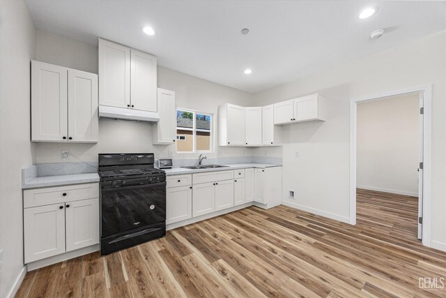 135 L St, Bakersfield, CA 93304 - kitchen with gas stove, light wood-style flooring, under cabinet range hood, light countertops, and white cabinets