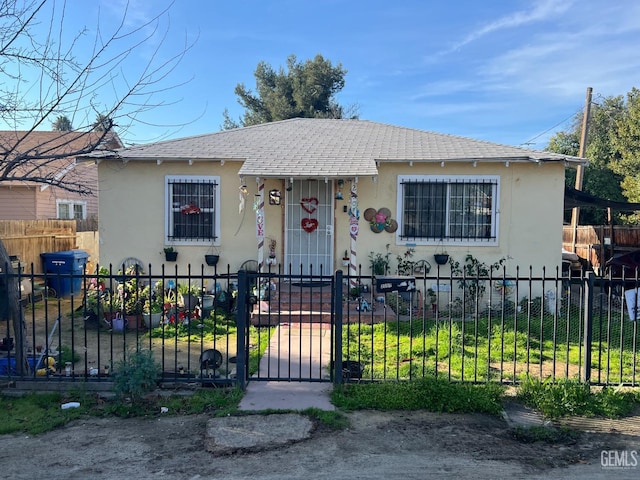 bungalow featuring a fenced front yard, a gate, and stucco siding