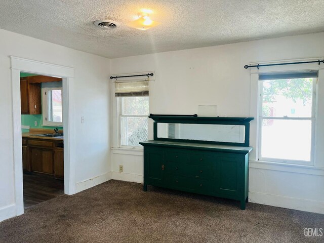 323 A St, Bakersfield, CA 93304 - unfurnished living room featuring dark colored carpet, a textured ceiling, a sink, healthy amount of natural light, and baseboards