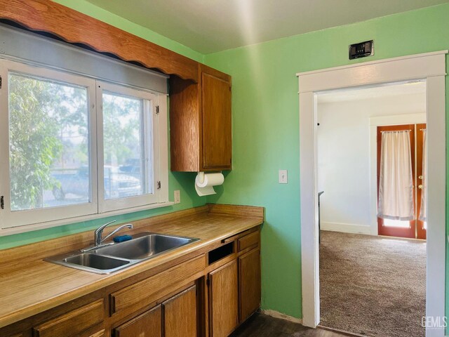 323 A St, Bakersfield, CA 93304 - kitchen with a sink, brown cabinetry, dark colored carpet, light countertops, and baseboards