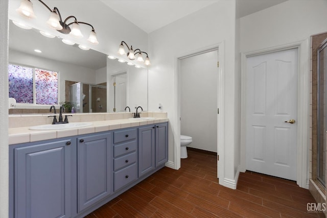 bathroom featuring toilet, a shower stall, a sink, and wood finished floors