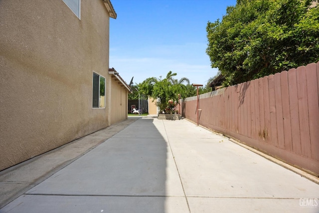 view of side of property with fence, stucco siding, and a patio area