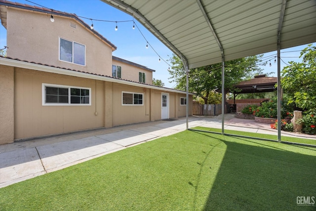 back of house with fence, stucco siding, a yard, and a patio area