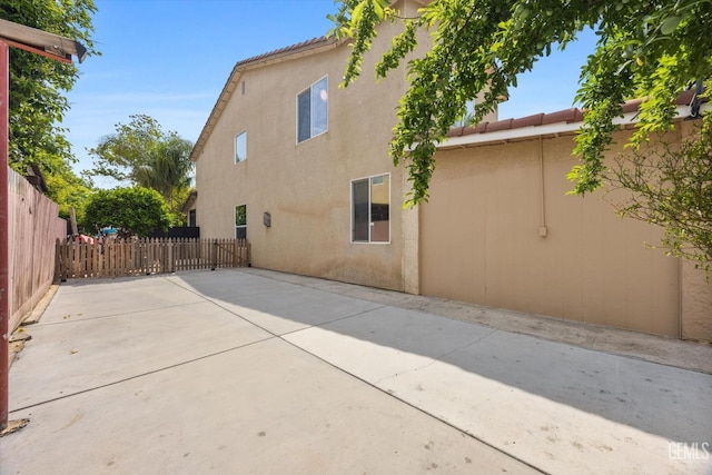 exterior space featuring a patio, fence, and stucco siding